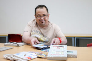 Man sitting at table reading book, looking at camera