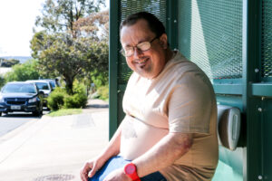Man sitting at bus stop, looking at camera