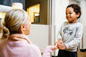 Young boy smiling standing in front of female teacher