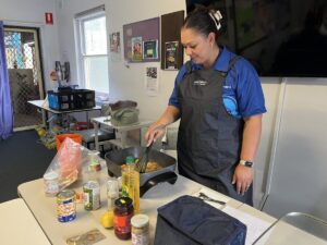 Woman standing behind barbeque cooking food